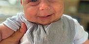 Oakley is registered to the contest to win money with this photo: baby, bib, child, closeup, clothing, cute, eyes, face, gray, hand, happy, head, indoor, infant, mouth, person, portrait, skin, smiling, white