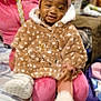 Journey is registered to the contest to win money with this photo: toddler, child, baby, person, indoor, fuzzy_coat, pink_headband, socks, seated, adult, lap, smiling, curly_hair, warm_clothing, blanket, bed, furniture, curtain, home, cozy