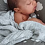baby, sleeping, blanket, cushion, cloud_pattern, infant, resting, soft_texture, peaceful, child, wrapped, cozy, indoors, portrait, head, face, newborn, relaxing, cute, toddler