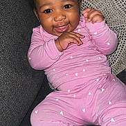 Kamiya is registered to the contest to win money with this photo: baby, child, smiling, pink_pajamas, heart_pattern, couch, pillow, indoor, happy, infant, cute, portrait, sitting, cozy, person, clothing, hand, face, head, young