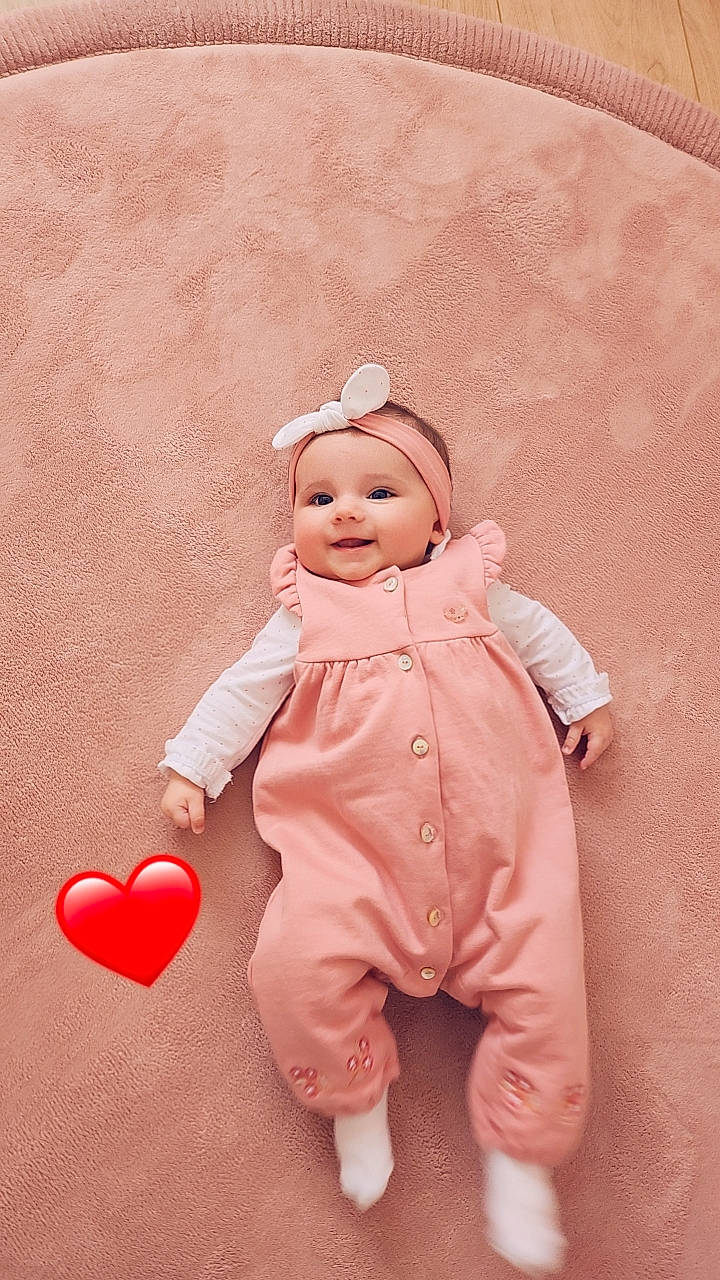 Mya a rejoint le concours — aidez-le/la à gagner de superbes lots ! baby, baby_toddler_clothing, balloon, carmine, child, costume, facial_expression, flooring, fun, fur, gesture, happy, hat, headgear, headwear, peach, person, pink, sitting, sleeve