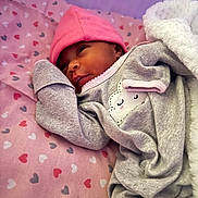 Terriana Marie is registered to the contest to win money with this photo: baby, newborn, pink_hat, grey_outfit, heart_pattern, blanket, sleeping, cute, infant, lying_down, soft_texture, cozy, child, adorable, resting, warm, face, headwear, bed, toddler