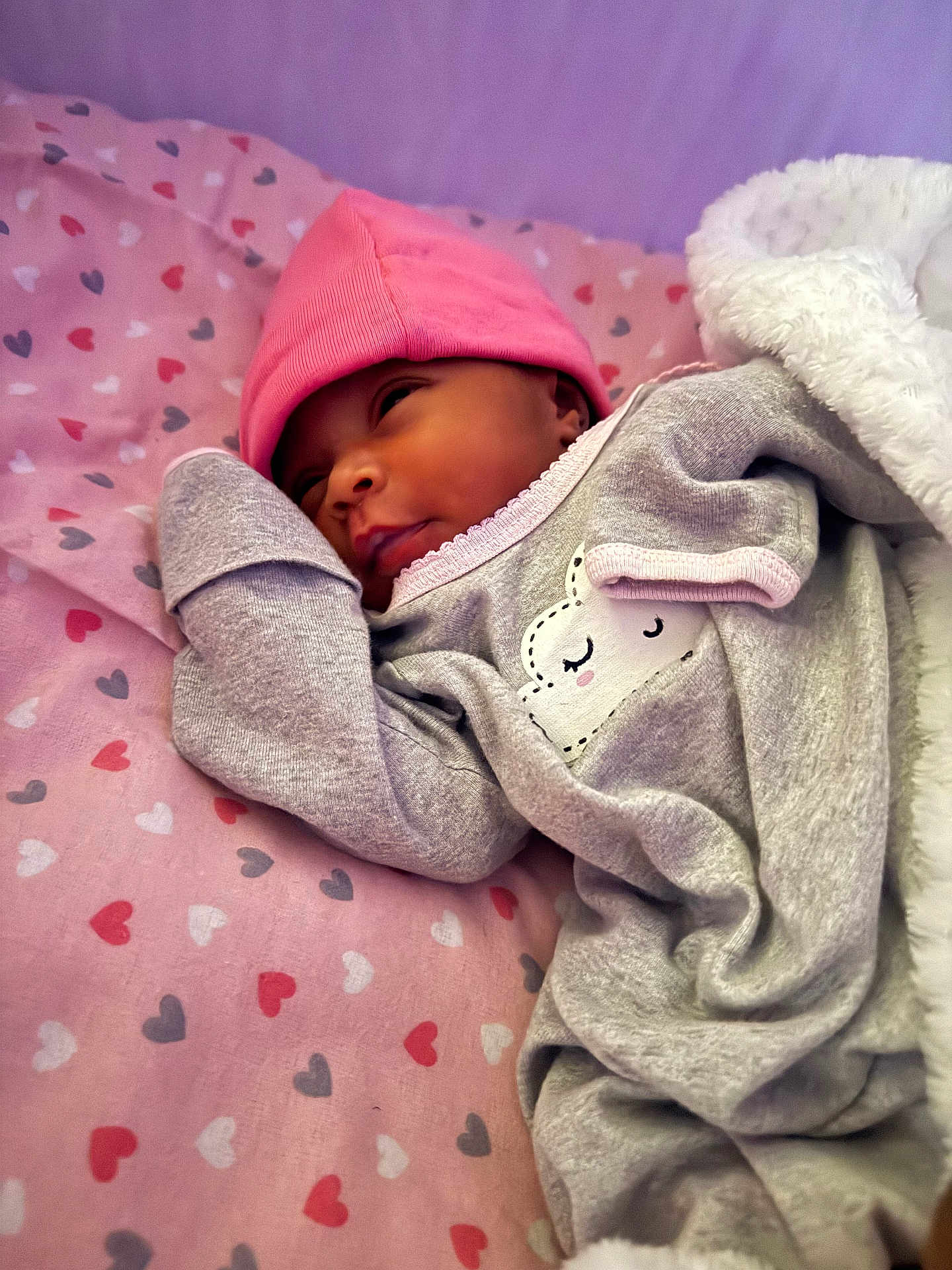 Terriana Marie is registered to the contest to win money with this photo: baby, newborn, pink_hat, grey_outfit, heart_pattern, blanket, sleeping, cute, infant, lying_down, soft_texture, cozy, child, adorable, resting, warm, face, headwear, bed, toddler