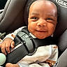 baby, car_seat, child, smile, infant, seatbelt, clothing, hand, face, safety, cute, happy, person, car_interior, closeup, young_child, curly_hair, expression, comfort, secure