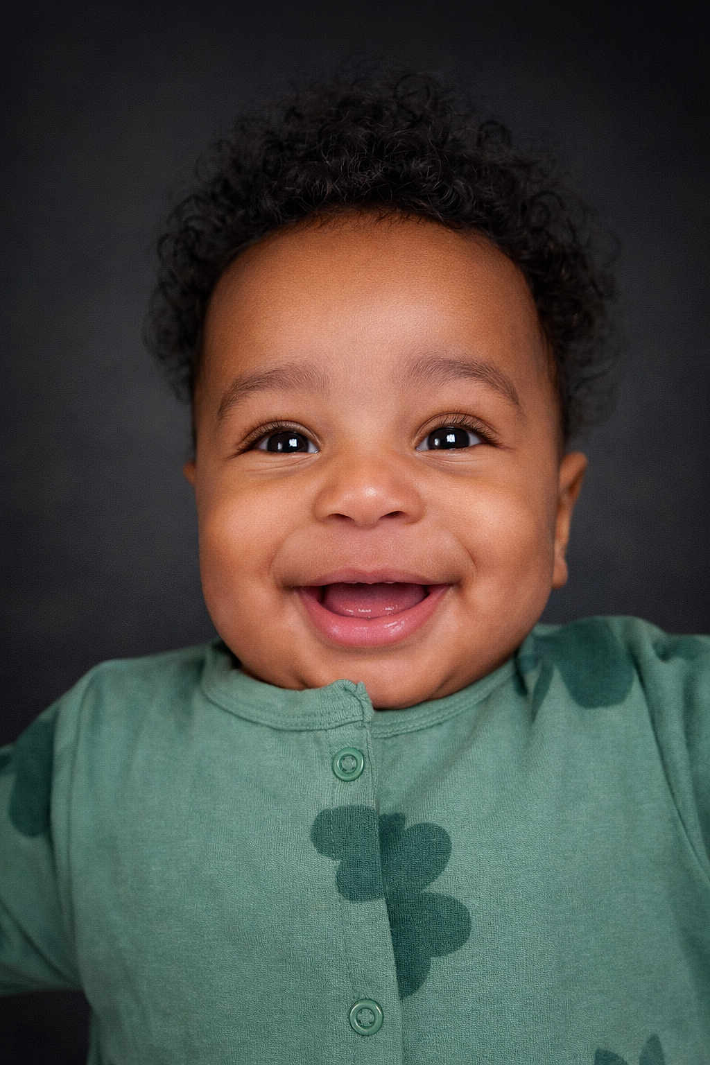 Elijah -Alejandro joined the competition — help win amazing prizes! baby, infant, child, smile, teeth, eyes, curly_hair, dimple, onesie, green_clothing, portrait, closeup, studio_background, happy, cheek, face, button, skin, front_lighting, cute
