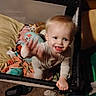 toddler, child, playpen, toy, stuffed_animal, blanket, carpet, clothing, hand, face, smile, indoor, baby, person, footwear, home, furniture, expression, motion_blur, happiness