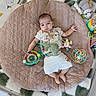 baby, child, toys, cushion, blanket, soft, indoor, infant, playtime, cute, comfort, lying_down, colorful, expression, clothing, floor, relaxing, person, young_child, peaceful