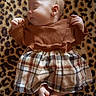 baby, sleeping, infant, plaid_skirt, brown_top, leopard_print, blanket, soft_texture, cute, peaceful, feet, hands, portrait, indoor, child, fashion, cozy, resting, newborn, comfortable