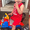 Nathaniel joined the competition — help win amazing prizes! toddler, child, toy_car, red_clothing, smiling, outdoor, porch, wooden_floor, door, playful, happy, cute, footwear, crocs, vehicle, person, casual, summer, fun, daylight