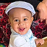 baby, child, smiling, face, cap, hat, bib, hand, table, person, background, floral_pattern, clothing, cute, happy, indoor, portrait, skin, headwear, infant
