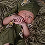 Dallas joined the competition — help win amazing prizes! baby, newborn, infant, sleepy, green_outfit, hat, fur_blanket, cute, small_hands, small_feet, soft_texture, portrait, indoors, cozy, resting, child, one_eye_open, plaid_pattern, button, closeup