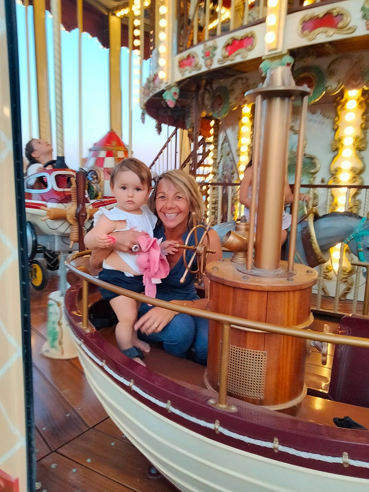 Lya a rejoint le concours — aidez-le/la à gagner de superbes lots ! amusement_park, amusement_ride, boat, boats_and_boating_equipment_and_supplies, carousel, event, fun, happy, joy, leisure, motor_vehicle, naval_architecture, nonbuilding_structure, outdoor_recreation, person, playground, recreation, smile, t_shirt, toddler