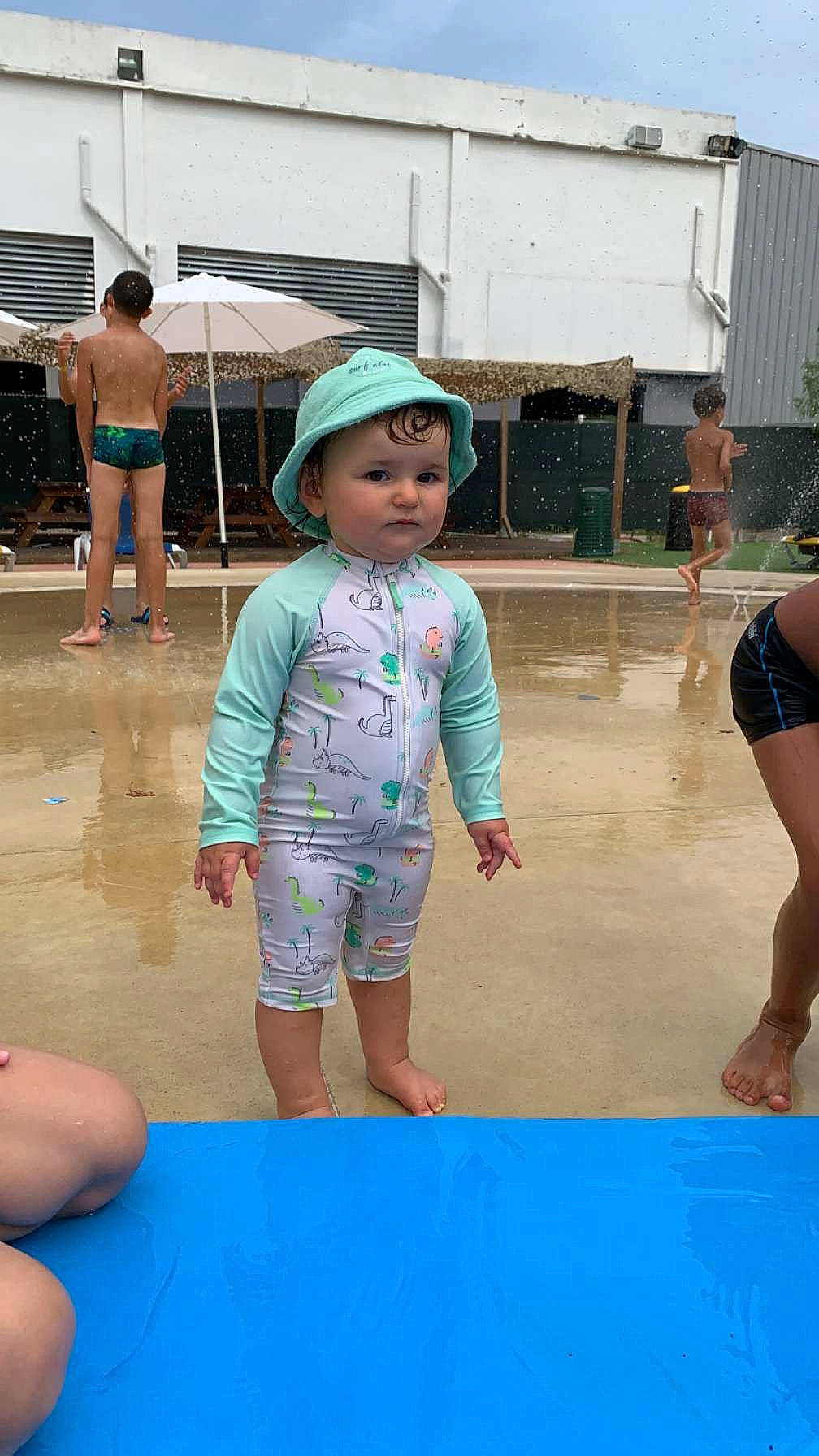 Lya participe au concours pour gagner de l'argent avec cette photo : barefoot, blue, child, flooring, foot, fun, headwear, human_leg, leg, leisure, person, pink, play, recreation, shorts, skin, standing, thigh, toddler, umbrella