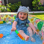 Albin a rejoint le concours — aidez-le/la à gagner de superbes lots ! toddler, child, pool, water, splashing, hat, swimsuit, toy, outdoor, garden, plants, summer, play, happy, smiling, barefoot, blue, inflatable_pool, sunlight, fun