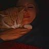 Munchie joined the competition — help win amazing prizes! cat, orange_cat, white_cat, pet, animal, person, woman, face, smile, cuddling, affection, sleepy, relaxed, indoor, dim_lighting, warm_lighting, portrait, closeup, cozy, blanket