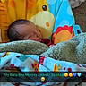 newborn, baby, infant, sleeping, face, portrait, blanket, swaddle, baby_seat, giraffe, colorful, cozy, indoors, home, text_overlay, emojis, parent_message, patterned_blanket, resting, cute