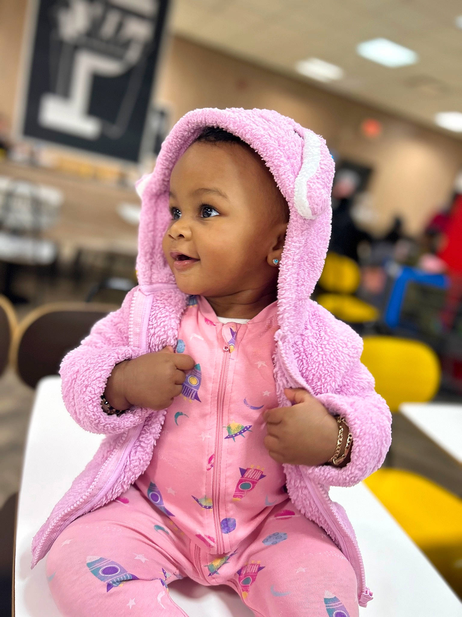 Sariyah is registered to the contest to win money with this photo: abdomen, baby, baby_toddler_clothing, cap, cheek, child, costume, dress, facial_expression, fun, happy, jacket, magenta, person, pink, purple, sitting, skin, sleeve, smile