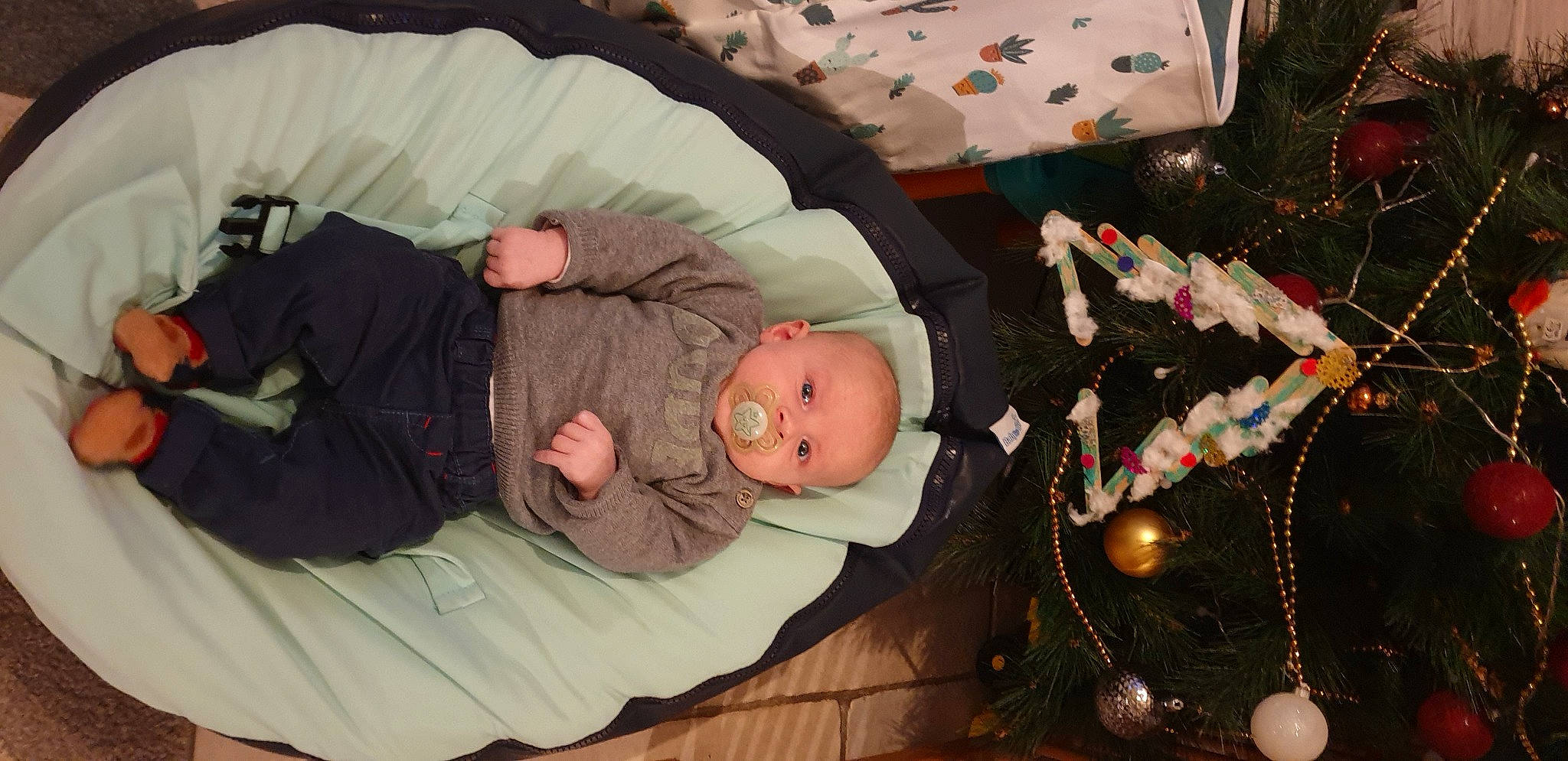 Adrian a rejoint le concours — aidez-le/la à gagner de superbes lots ! baby, baby_toddler_clothing, christmas, christmas_decoration, christmas_eve, christmas_lights, christmas_ornament, christmas_tree, comfort, head, holiday, holiday_ornament, human, lap, mammal, nap, nose, ornament, person, sleep