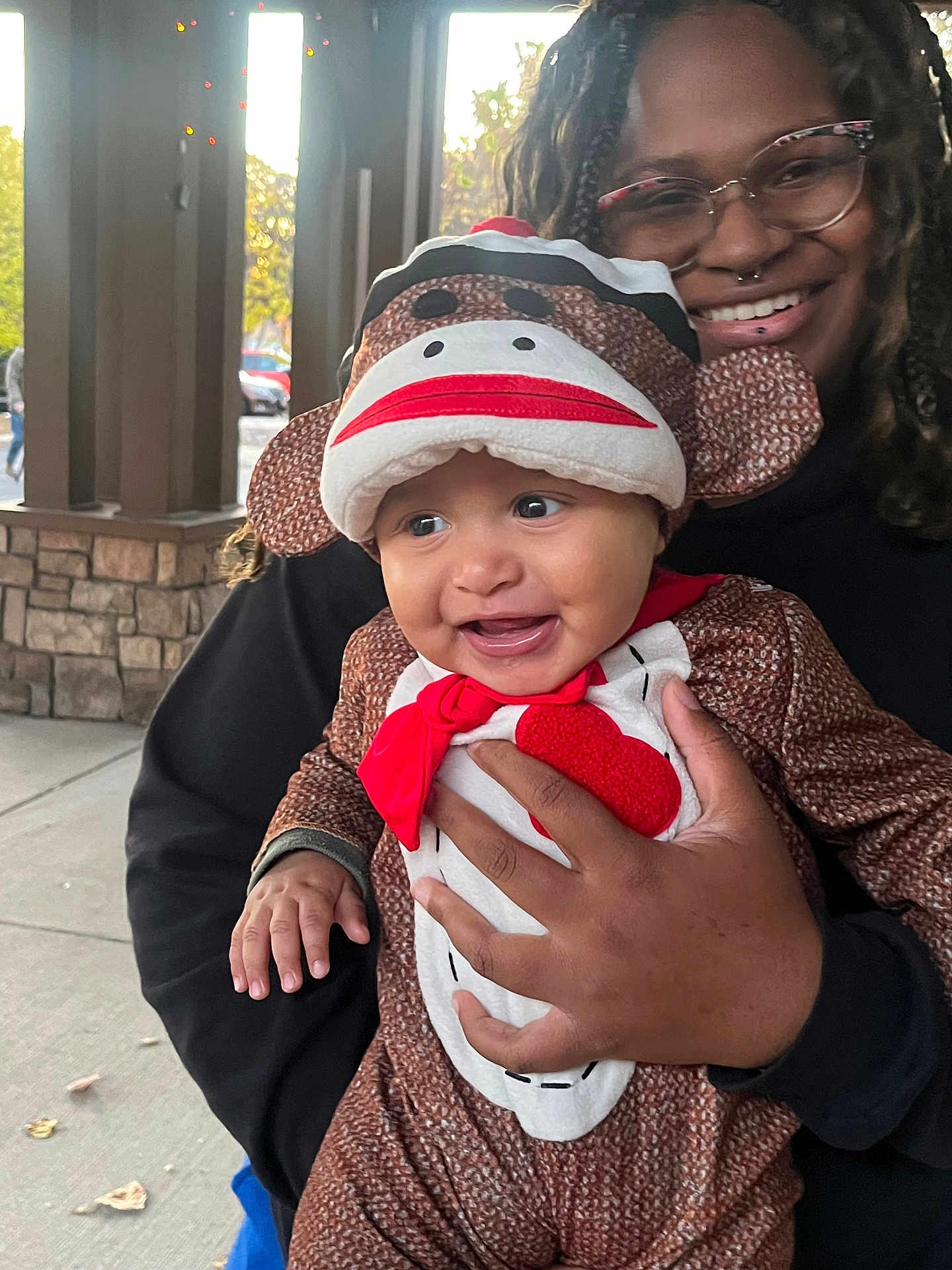 Dandre joined the competition — help win amazing prizes! baby, child, costume, sock_monkey, adult, glasses, smile, outdoor, person, holding, joyful, happy, face, hand, clothing, hood, portrait, daylight, building, window