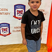 Chase joined the competition — help win amazing prizes! child, boy, portrait, tshirt, shorts, school, background, indoor, smile, face, person, standing, logo, text, shoes, curly_hair, earrings, floor, banner, casual_clothing