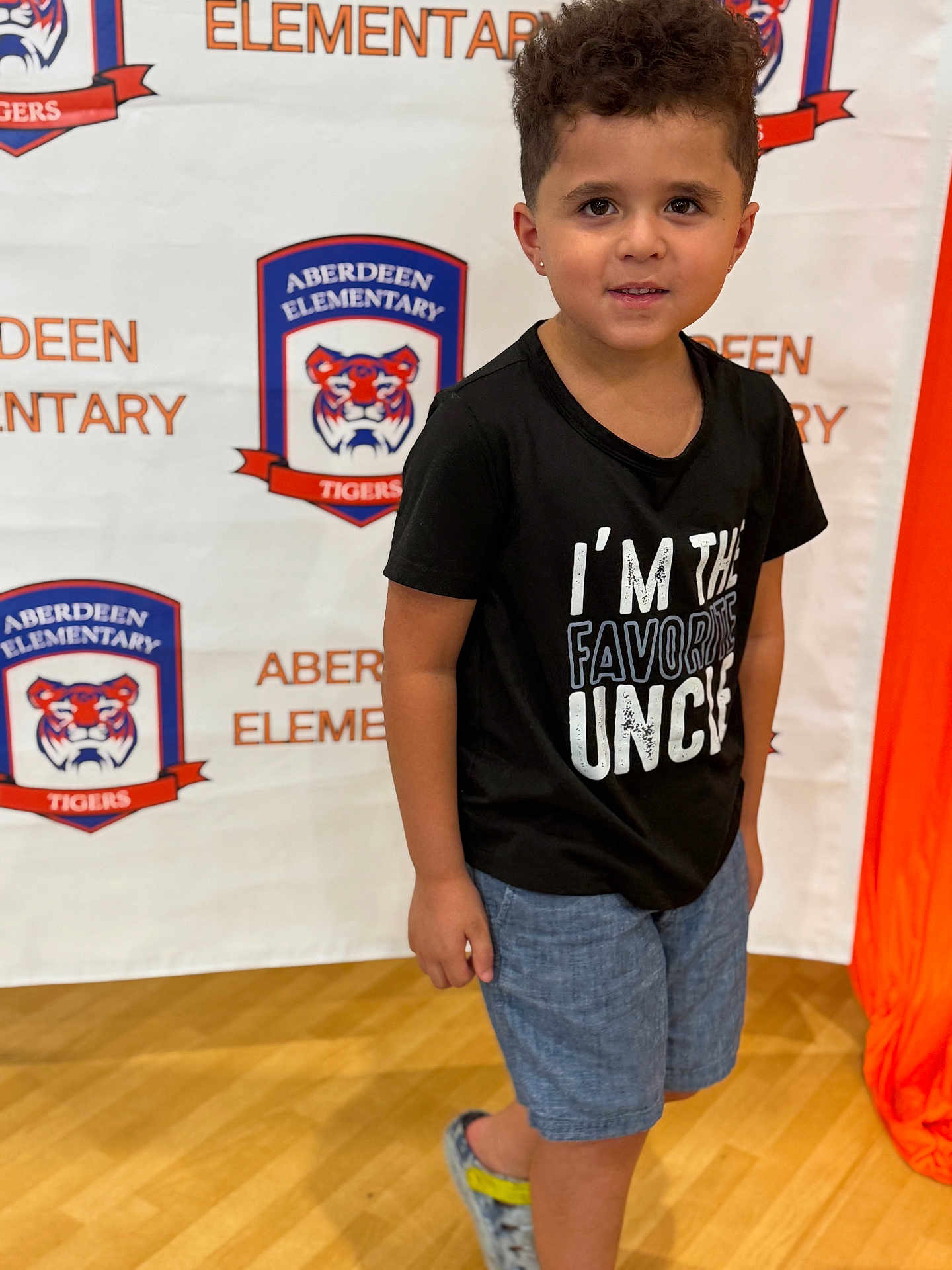 Chase joined the competition — help win amazing prizes! child, boy, portrait, tshirt, shorts, school, background, indoor, smile, face, person, standing, logo, text, shoes, curly_hair, earrings, floor, banner, casual_clothing