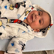 Jefferson is registered to the contest to win money with this photo: baby, child, smiling, blanket, hooded_blanket, cartoon_characters, white, soft_texture, lying_down, comfortable, cute, infant, face, portrait, indoors, warm, happy, cozy, clothing, person