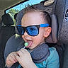 Phoenix is registered to the contest to win money with this photo: toddler, child, car_seat, sunglasses, lollipop, blue, hair, spiky_hair, seatbelt, car_interior, window, daylight, happy, cute, casual_clothing, smiling, headrest, person, fun, portrait
