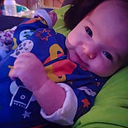 Clarence is registered to the contest to win money with this photo: baby, child, close_up, colorful_clothing, cozy, cushion, cute, face, green, hand, happy, indoors, infant, onesie, pattern, portrait, resting, sleepwear, smile, soft_lighting