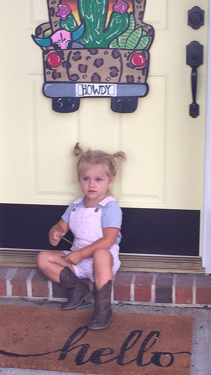 Scarlett is registered to the contest to win money with this photo: art, child, flooring, fun, happy, hat, human_leg, knee, leisure, person, picture_frame, pink, recreation, room, sandal, shorts, sitting, sock, t_shirt, toddler