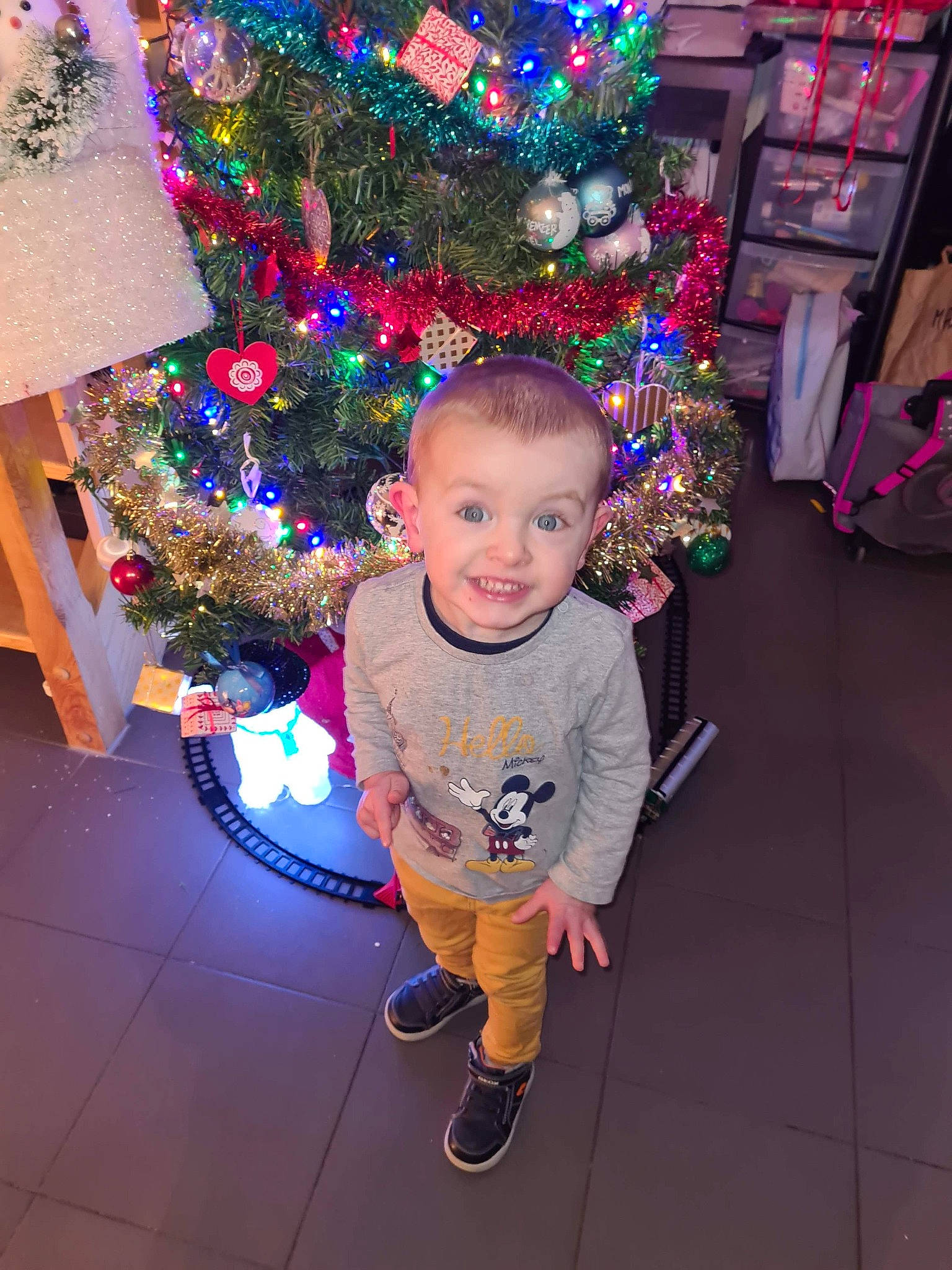 Noé participe au concours pour gagner de l'argent avec cette photo : baby_toddler_clothing, child, christmas, christmas_decoration, christmas_eve, christmas_lights, christmas_ornament, christmas_tree, cool, floor, flooring, holiday, holiday_ornament, interior_design, joy, ornament, person, pink, shelf, sneakers