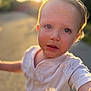 toddler, child, face, outdoor, sunlight, scribbles, expression, white_shirt, portrait, daylight, skin, young_child, curious, blurred_background, sunset, casual_clothing, human, person, head, closeup