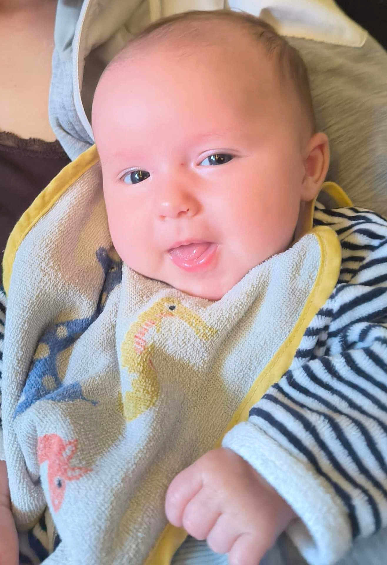 Maéna participe au concours pour gagner de l'argent avec cette photo : baby, infant, face, tongue, bib, striped_clothing, hand, cute, person, child, smiling, skin, cheeks, eyes, expression, holding, fabric, clothing, closeup, portrait