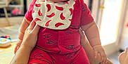 Jay is registered to the contest to win money with this photo: baby, bib, child, chubby, curious_toddler, cute, face, hand, holding, indoor, infant, kitchen, light, person, red_clothing, shorts, smile, table, tattoo, window