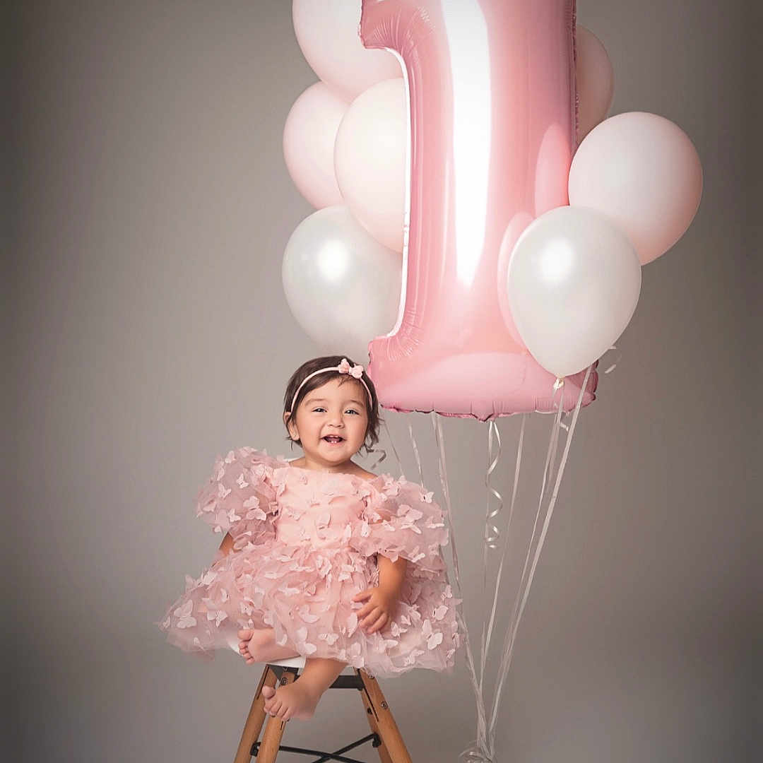 Masal a rejoint le concours — aidez-le/la à gagner de superbes lots ! balloons, barefoot, birthday, celebration, child, cute, fashion, girl, happy, headband, indoor, number_one_balloon, party, pastel_colors, pink_dress, portrait, smiling, studio, toddler, wooden_stool