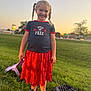 Braylee Selby joined the competition — help win amazing prizes! blue_shirt, braids, casual_clothing, child, evening, field, girl, grass, happy, jacket, nature, outdoor, person, playful, portrait, red_skirt, smiling, sneakers, sunset, toy
