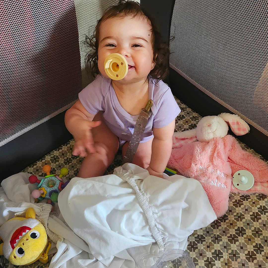Destiny is registered to the contest to win money with this photo: baby, blanket, child, childhood, cloth, cute, face, floor, happy, indoor, infant, onesie, pacifier, play, playpen, plush_toy, smiling, stuffed_animal, toddler, toy