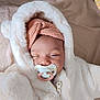 baby, pacifier, headband, white_jacket, sleeping, cozy, soft_texture, infant, cute, child, warm_clothing, indoor, portrait, baby_fashion, relaxed, close_up, face, blanket, zipped_jacket, peaceful