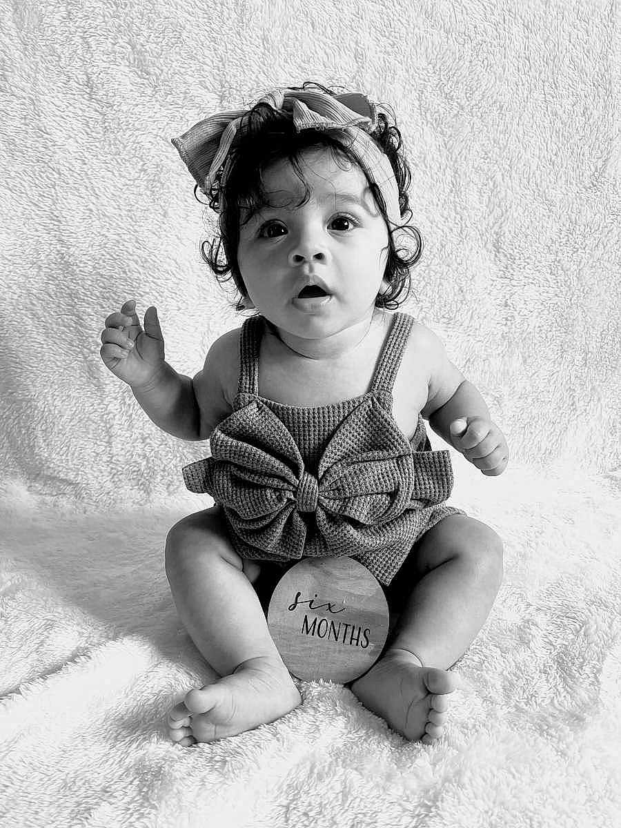 Jaleana is registered to the contest to win money with this photo: adorable, baby, big_eyes, black_and_white, bow, child, clothing, curly_hair, cute, expression, headband, indoor, infant, portrait, sitting, six_months, soft_blanket, studio, wooden_sign, young
