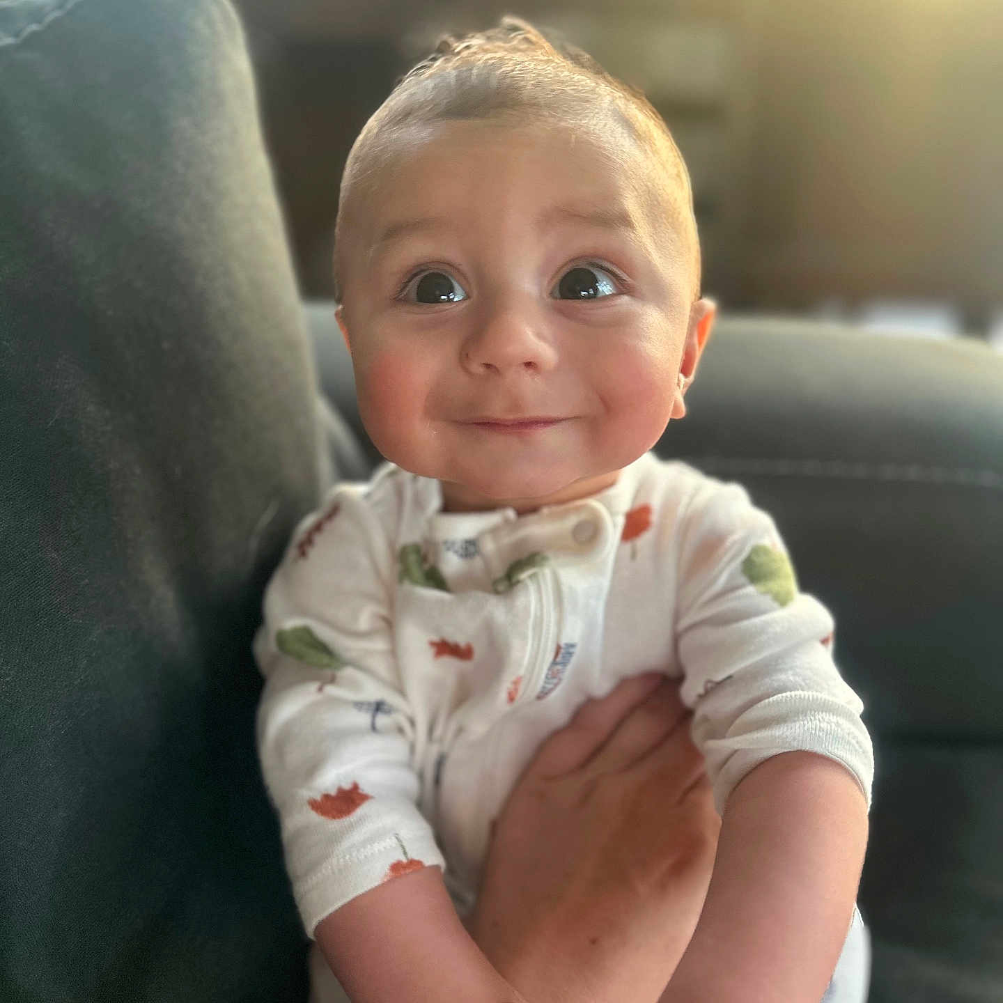 Sawyer is registered to the contest to win money with this photo: baby, child, couch, cozy, cute, expression, eyes, face, furniture, hand, holding, indoors, infant, onesie, person, portrait, sitting, skin, smile, warm_light