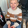 Sacha a rejoint le concours — aidez-le/la à gagner de superbes lots ! child, boy, smiling, indoor, sitting, lollipop, sweater, jeans, bucket, floor, chair, gaming_chair, toy, happy, person, wooden_floor, bag, container, casual_clothing, home