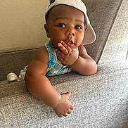 Makhai is registered to the contest to win money with this photo: baby, child, face, cap, hat, overalls, couch, furniture, indoor, curious, hand, skin, portrait, person, clothing, seat, expression, cute, young, infant