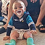 Riley is registered to the contest to win money with this photo: baby, child, smiling, messy_face, yogurt, cream, hoodie, socks, diaper, floor, happy, hands, legs, nike_slippers, indoor, person, playing, cute, toddler, blue_clothing