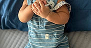 Phoenix joined the competition — help win amazing prizes! baby, infant, smiling, blue_striped_clothing, romper, pacifier, bed, bedding, pillow, happy, cute, child, person, indoor, portrait, hands, feet, socks, face, lying_down