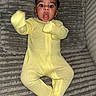 Phoenix is registered to the contest to win money with this photo: baby, blanket, child, clothing, cute, expression, face, funny, happy, indoor, infant, lying_down, person, portrait, small, soft, surprised, textured, yellow_onesie, young