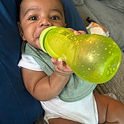 Phoenix joined the competition — help win amazing prizes! baby, bib, bottle, child, chubby, couch, curious, cushion, cute, eyes, face, green, hand, holding, indoors, infant, person, sitting, skin, white_clothing