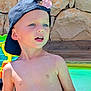 child, boy, cap, flower, shirtless, pool, water, rock_wall, outdoor, summer, sunlight, blue_eyes, toy, play, happy, skin, nature, daylight, casual, portrait