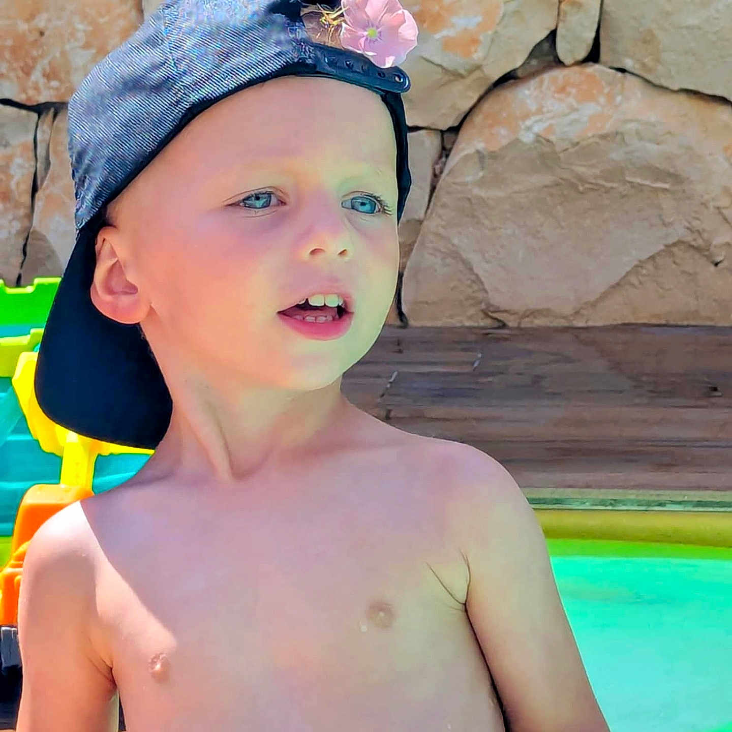 Nino a rejoint le concours — aidez-le/la à gagner de superbes lots ! blue_eyes, boy, cap, casual, child, daylight, flower, happy, nature, outdoor, play, pool, portrait, rock_wall, shirtless, skin, summer, sunlight, toy, water