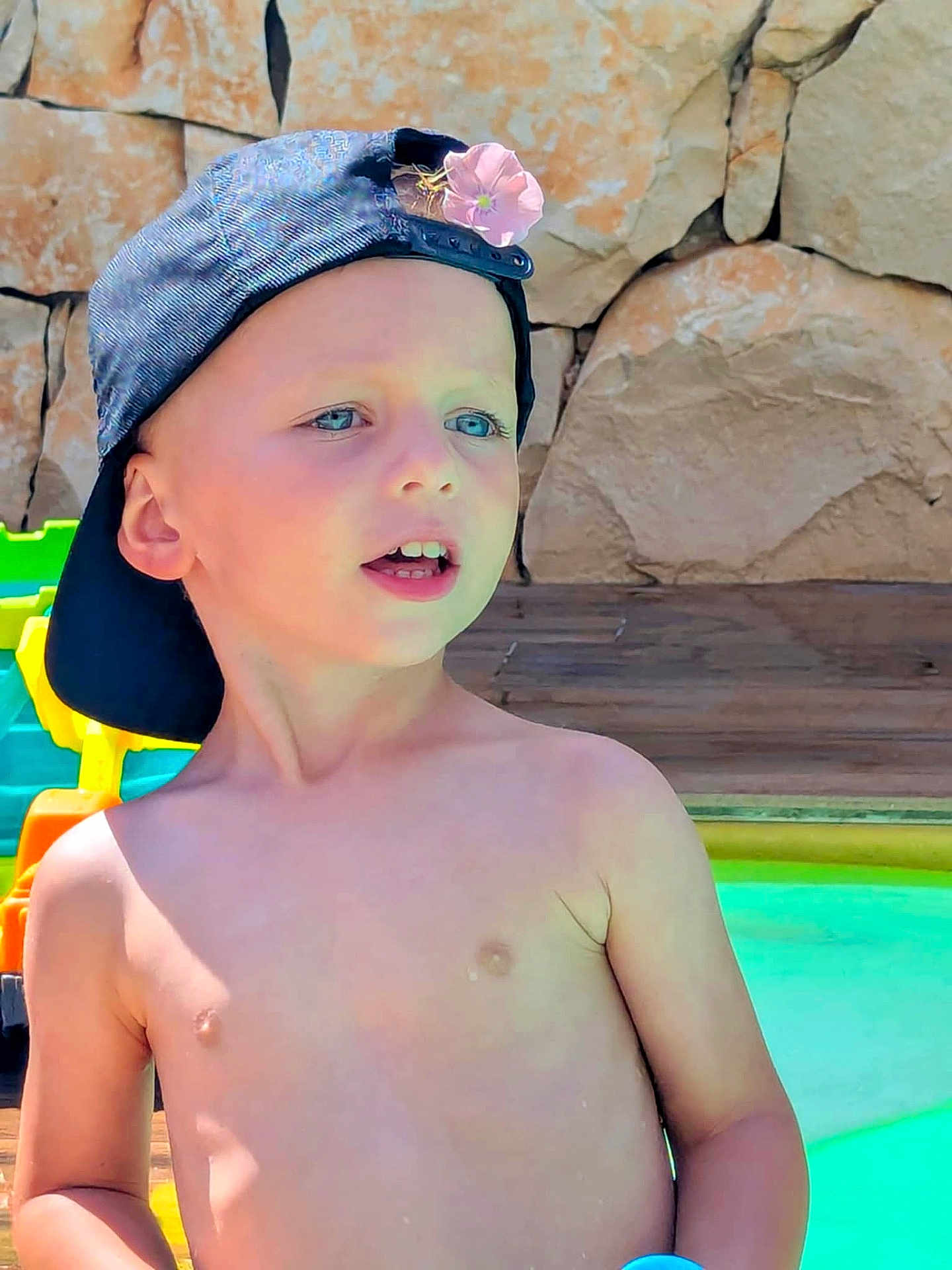 Nino a rejoint le concours — aidez-le/la à gagner de superbes lots ! child, boy, cap, flower, shirtless, pool, water, rock_wall, outdoor, summer, sunlight, blue_eyes, toy, play, happy, skin, nature, daylight, casual, portrait