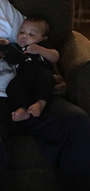 Asher is registered to the contest to win money with this photo: arm, baby, black, cheek, child, eye, finger, hand, head, human, human_body, interaction, joint, leg, mouth, neck, nose, person, sitting, skin