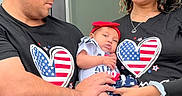 Maisy is registered to the contest to win money with this photo: baby, man, woman, family, holding, outdoor, toddler, clothing, headwear, love, affection, matching_outfits, red, black, casual, portrait, smiling, people, hat, bracelet